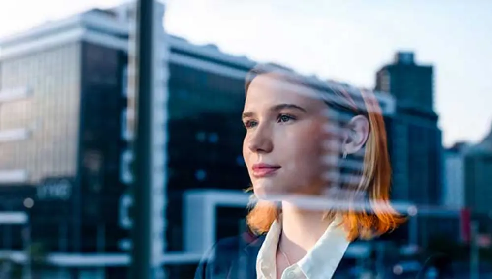 A woman appears to look out of and into a building at the same time.