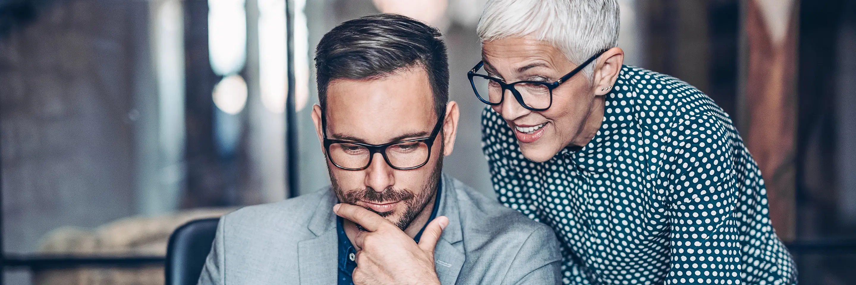 A man and a woman talk in front of a laptop.